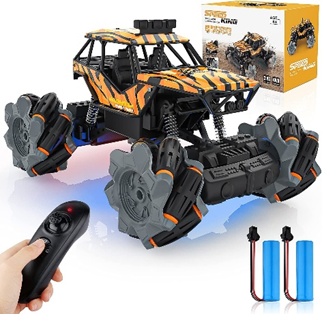 Image Description: A photograph of a black and yellow toy car being controlled by a hand holding a small black controller in the left corner. The blue battery packs and yellow box are also present on the right side of the picture.  
